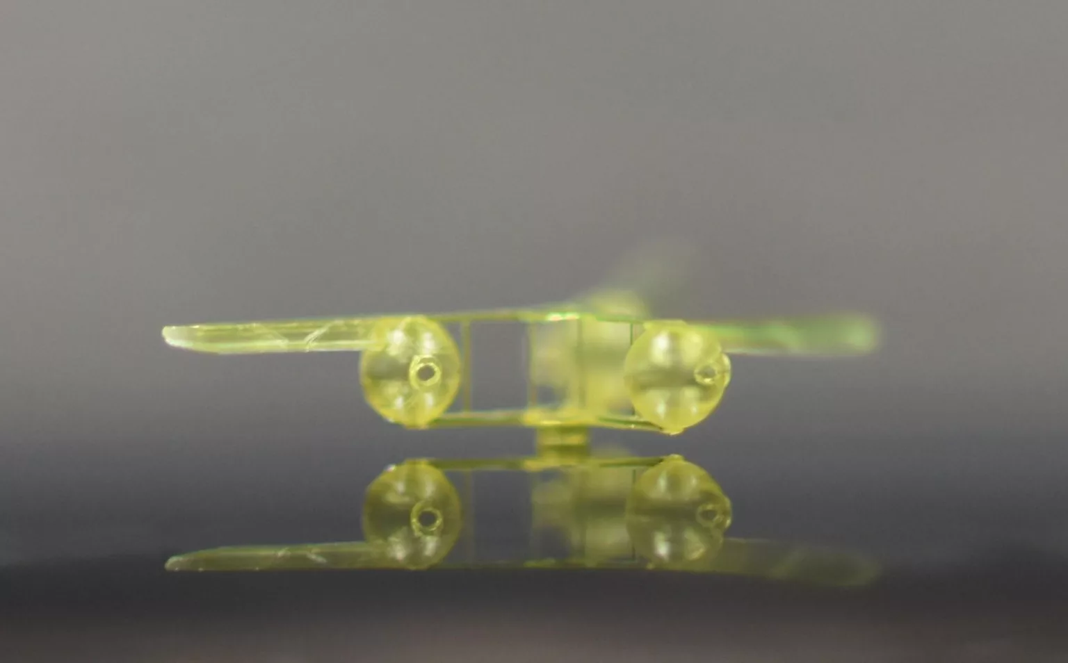 Close-up of a yellow three-blade rotor on a reflective surface.